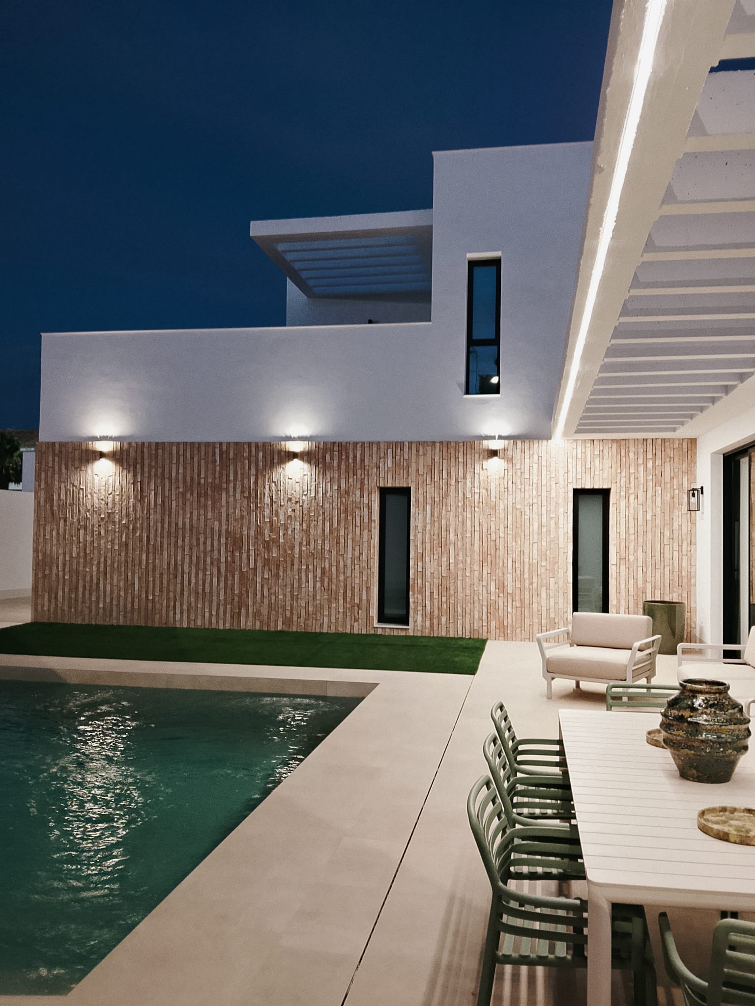 Fachada revestida junto a la piscina y el porche